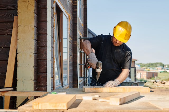 Man using a drill on a house renovation construction site.