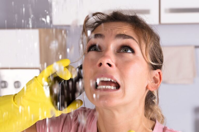 shocked woman looking up at leak calling a tradie